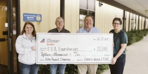Dennis Walsh presents a $15,000 check to the North Dakota FFA Foundation, with Kayla Hart, Reuben Weigelt, and Beth Allen standing beside him.