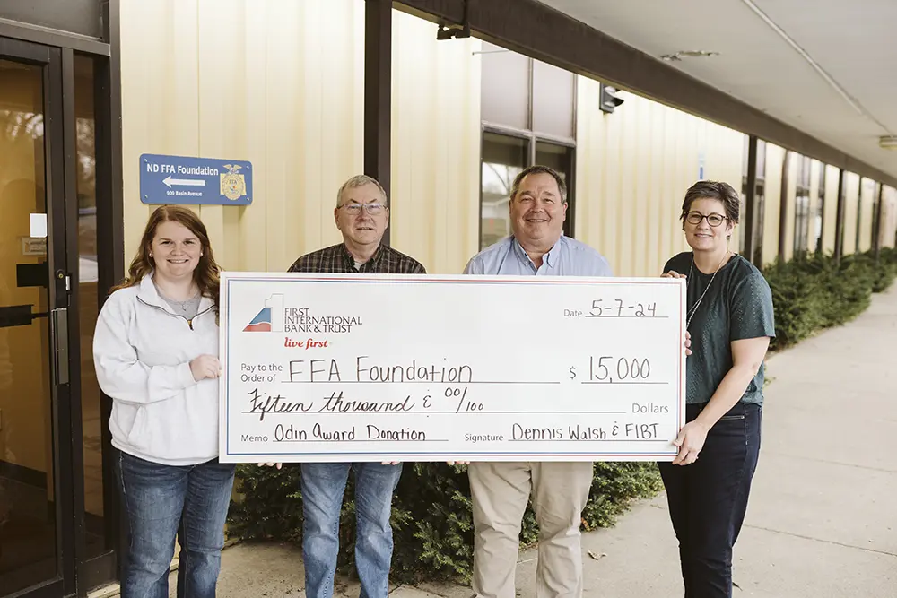 Dennis Walsh presents a $15,000 check to the North Dakota FFA Foundation, with Kayla Hart, Reuben Weigelt, and Beth Allen standing beside him.